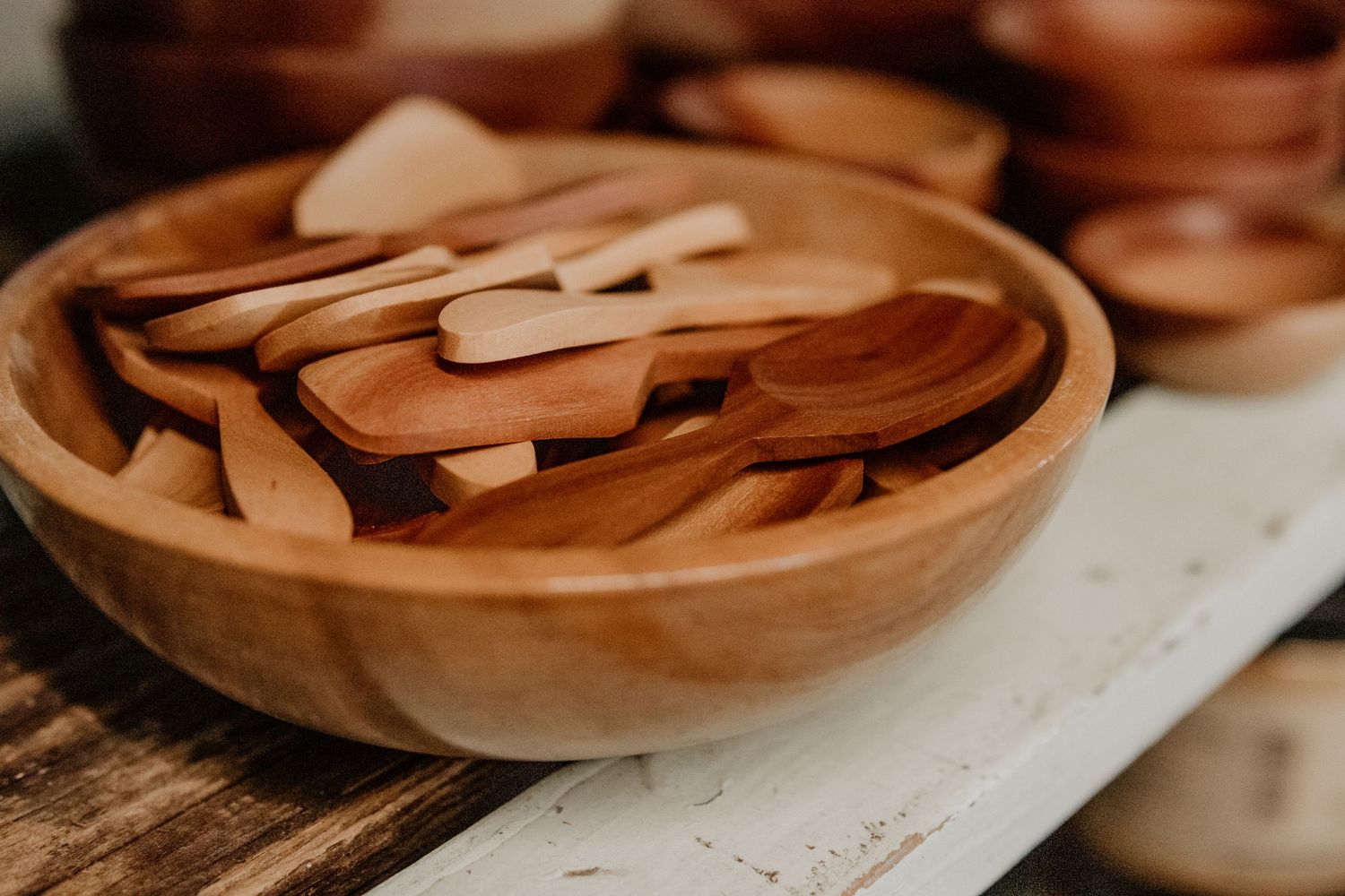 Collection of handcrafted wooden bowls and utensils arranged on rustic wooden surface.