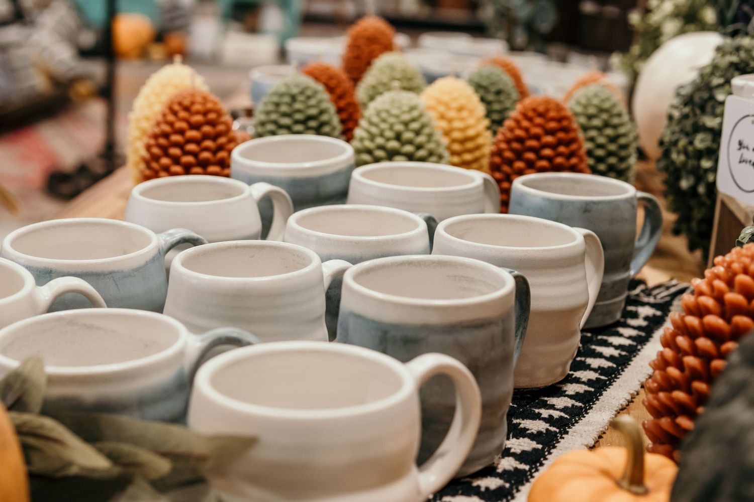 White ceramic bowls and decorative pinecones arranged in rustic autumn display.