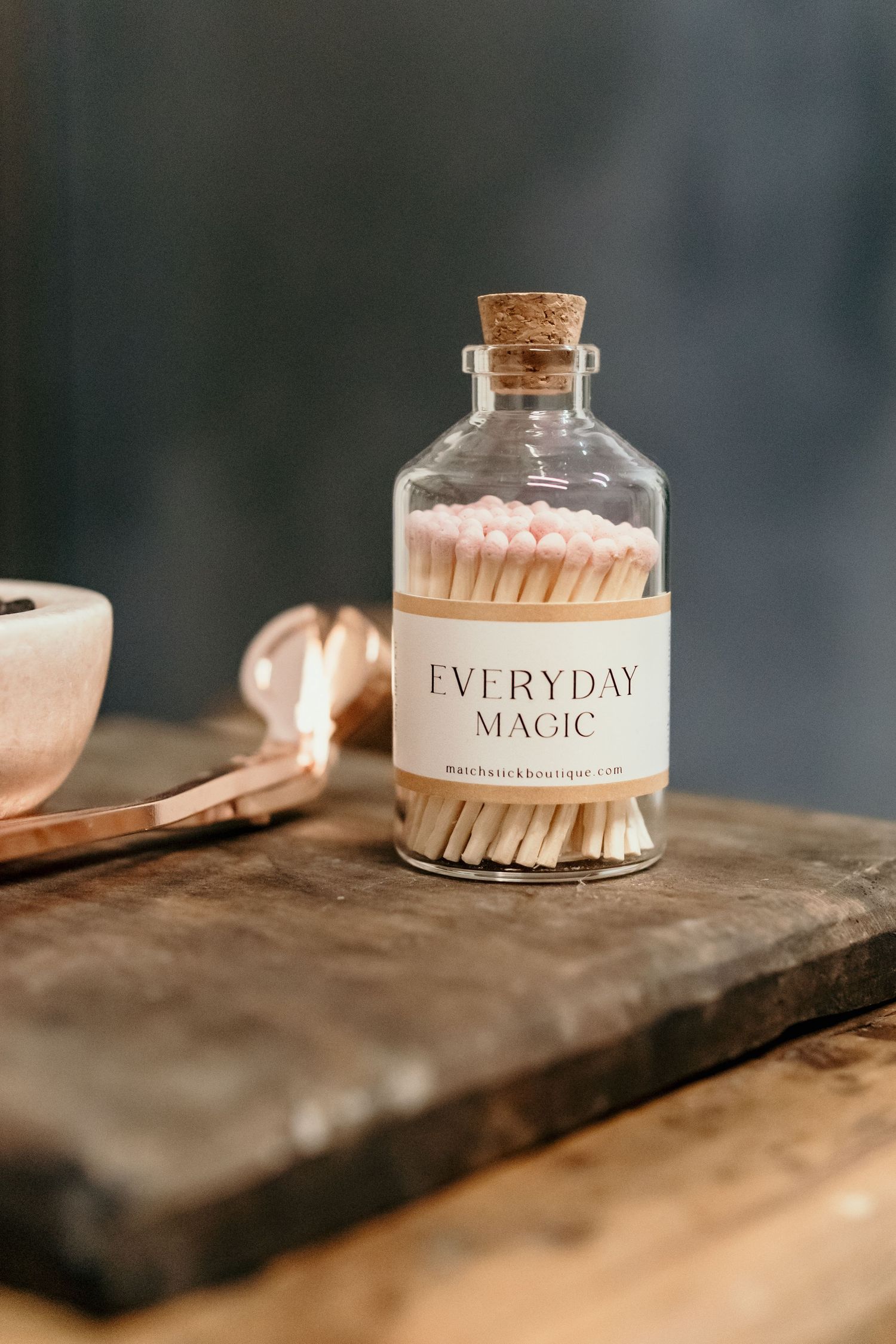 Glass jars labeled 'Everyday Magic' displayed on weathered wooden surface.