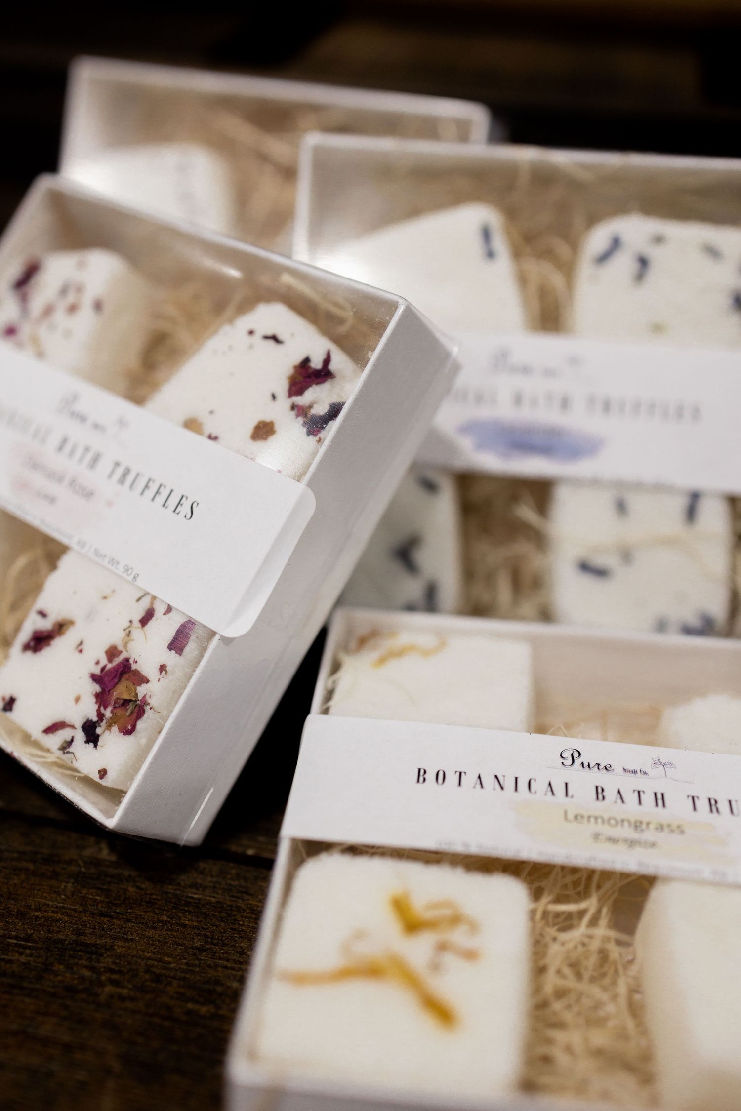 White boxes of botanical bath products arranged in rows on display.