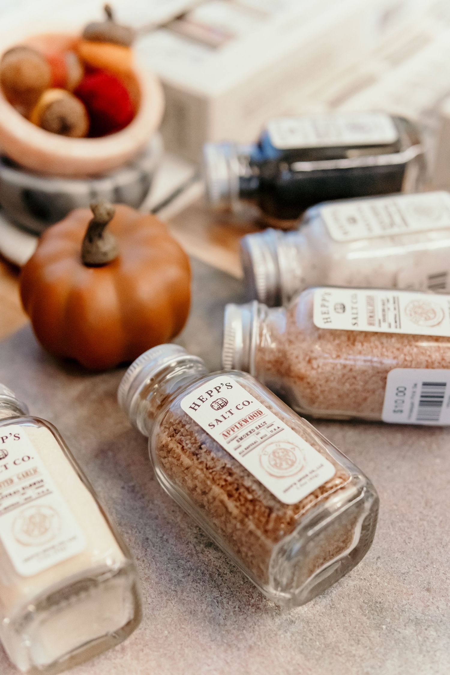 Glass spice jars filled with seasonings displayed alongside decorative autumn pumpkins.