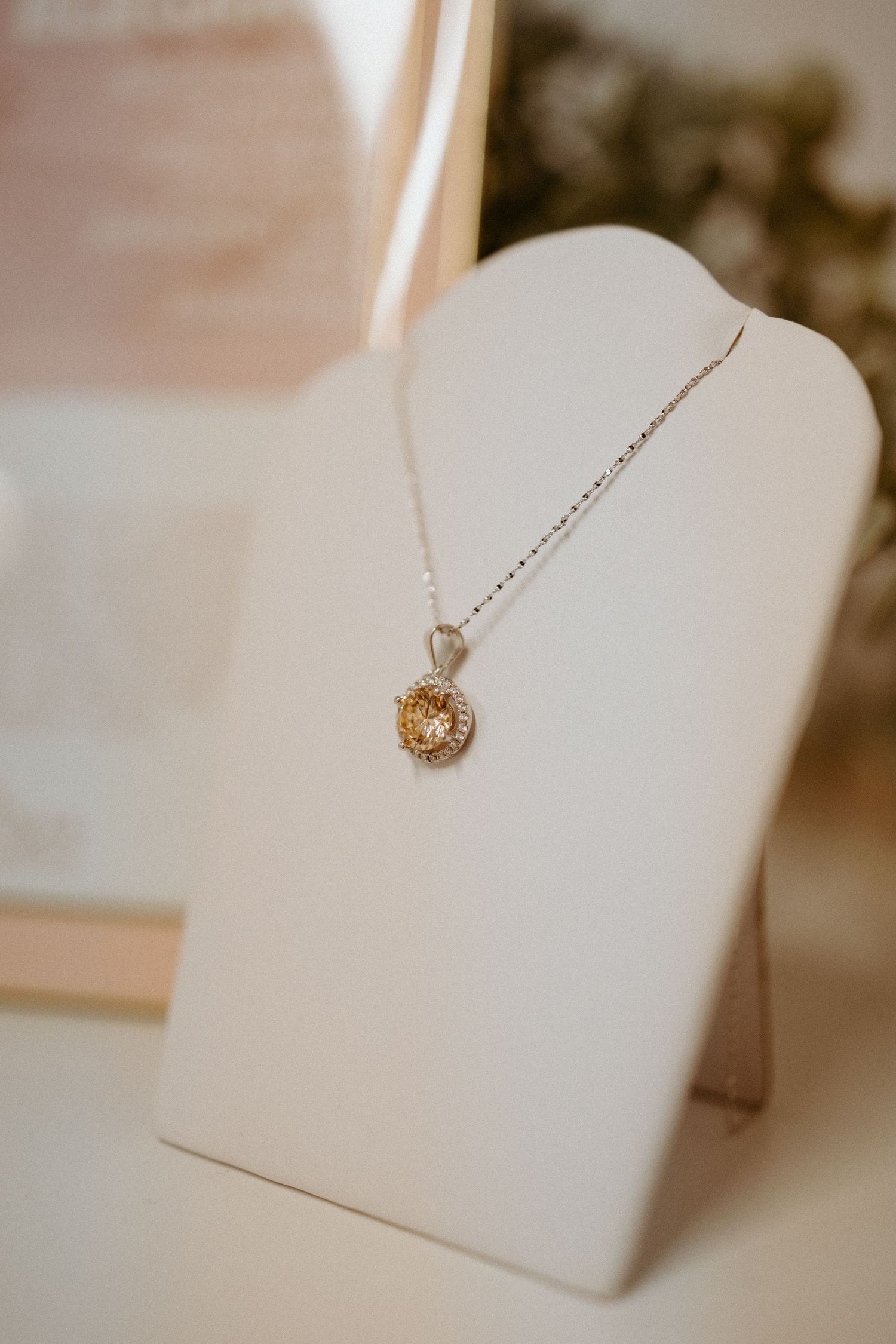Delicate gold necklaces displayed on white jewelry stands in soft lighting.