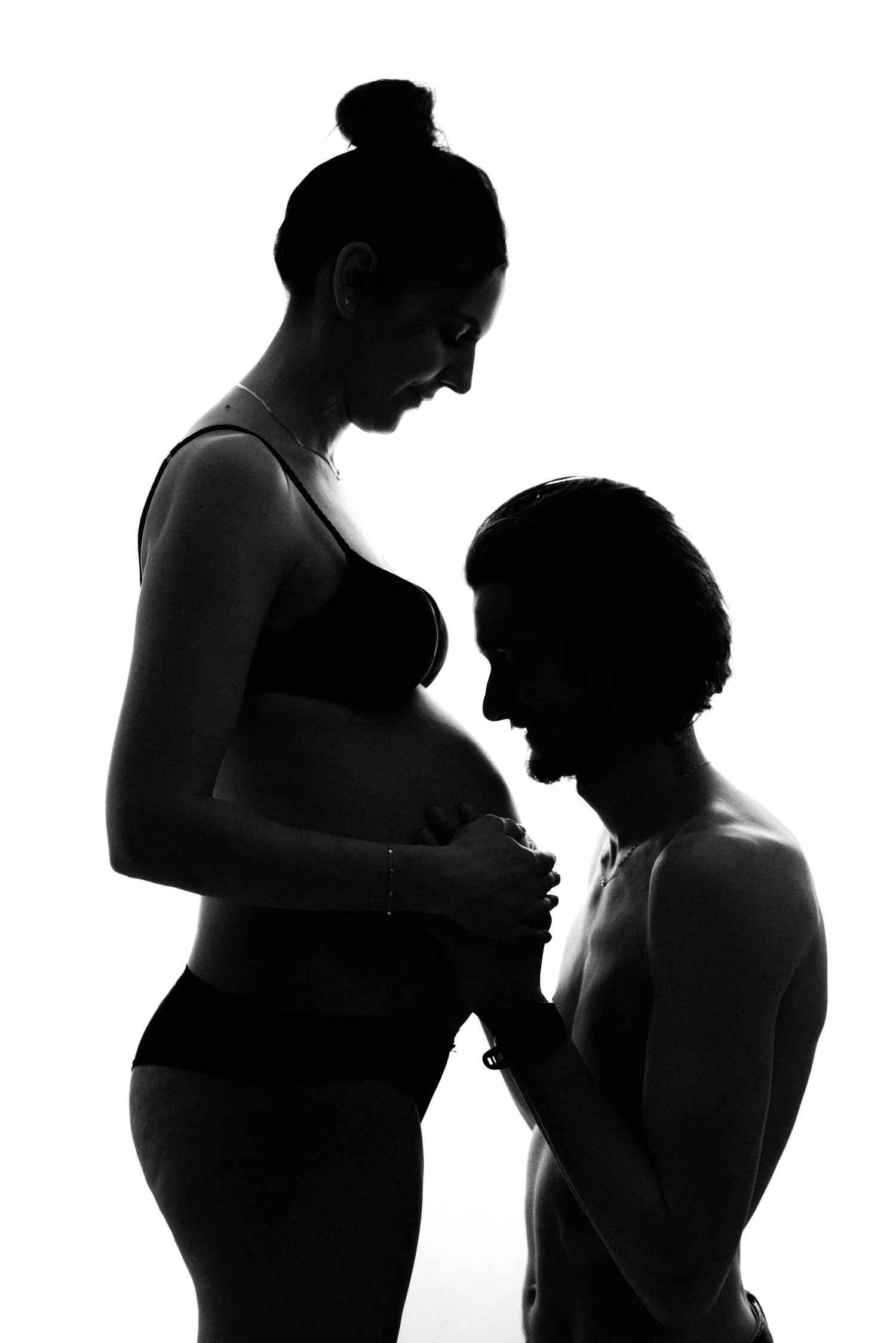 Artistic silhouette of a tender pregnancy moment between two people.
