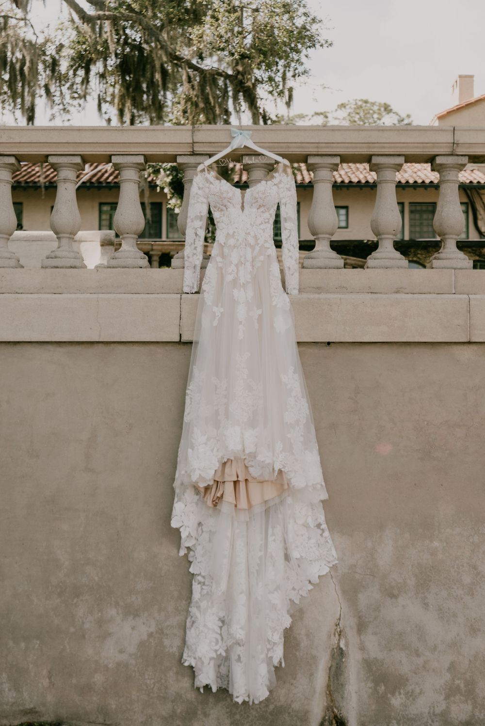 image of bride's dress hanging over the side of a historic cement wall at the Club Continental in Orange Beach Florida