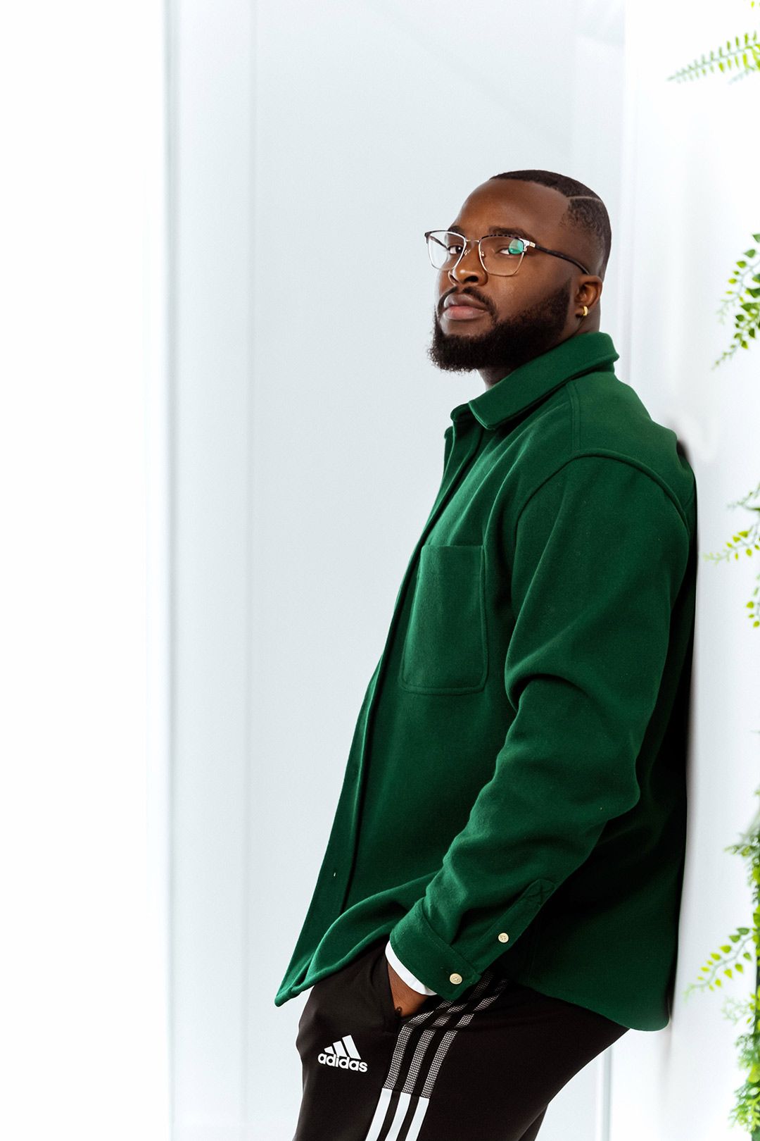 A young man in green shirt resting his back on the wall and posing for the camera