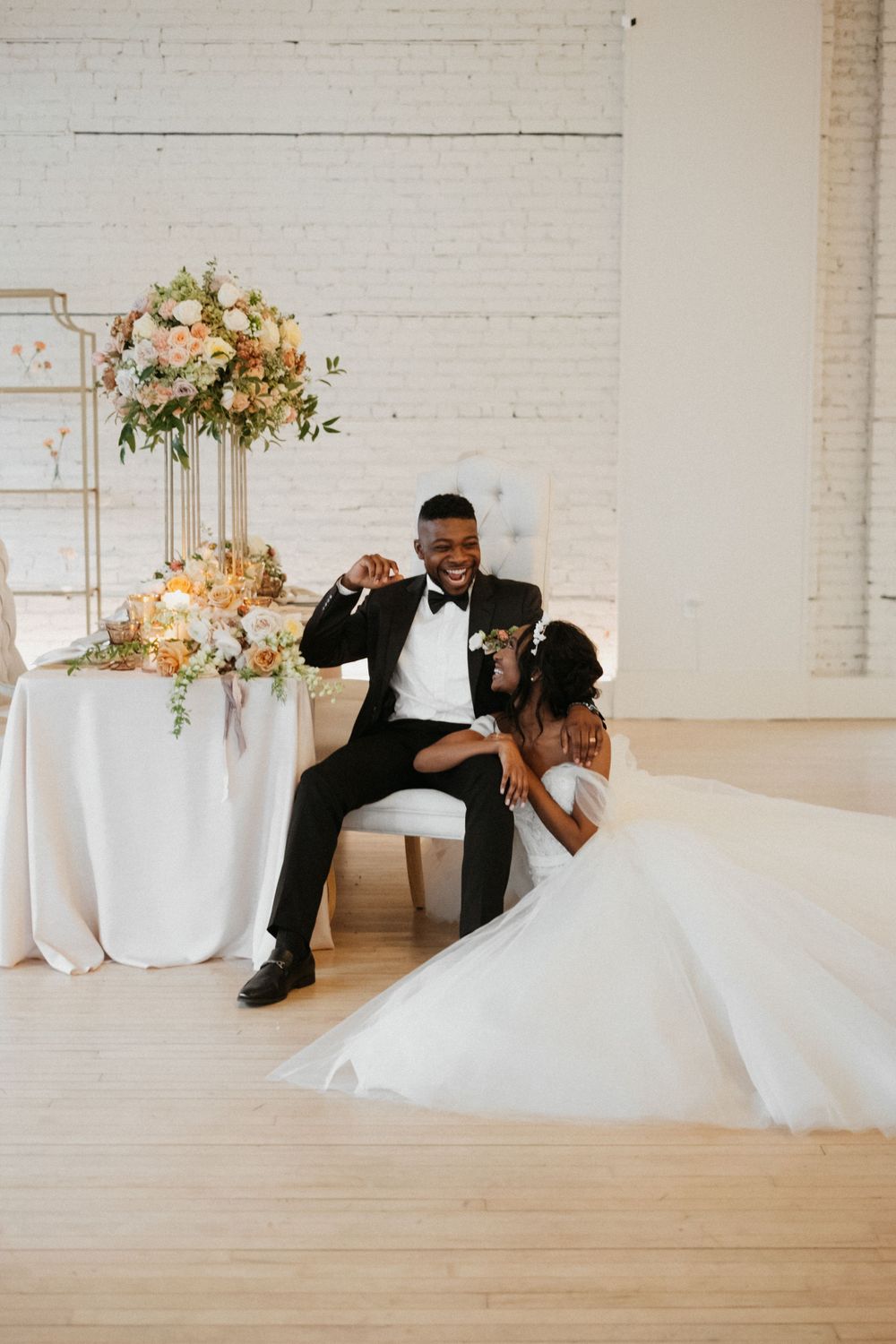A wedding celebration scene with elegant table decor and newlyweds posing by floral arrangements.