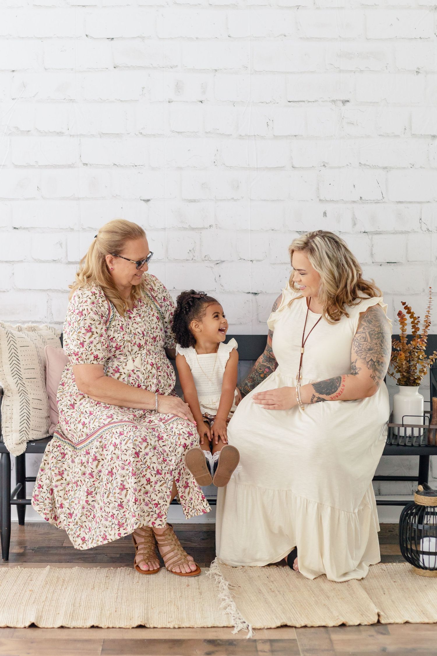 Casual indoor portrait showing joyful interaction on beige bench against white wall.
