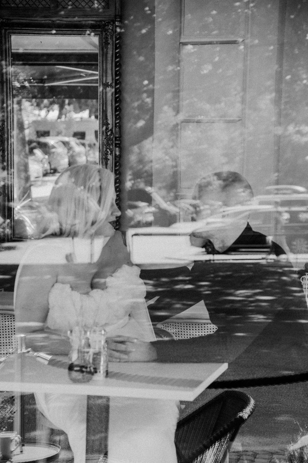 Black and white artistic photo showing reflections through cafe window.