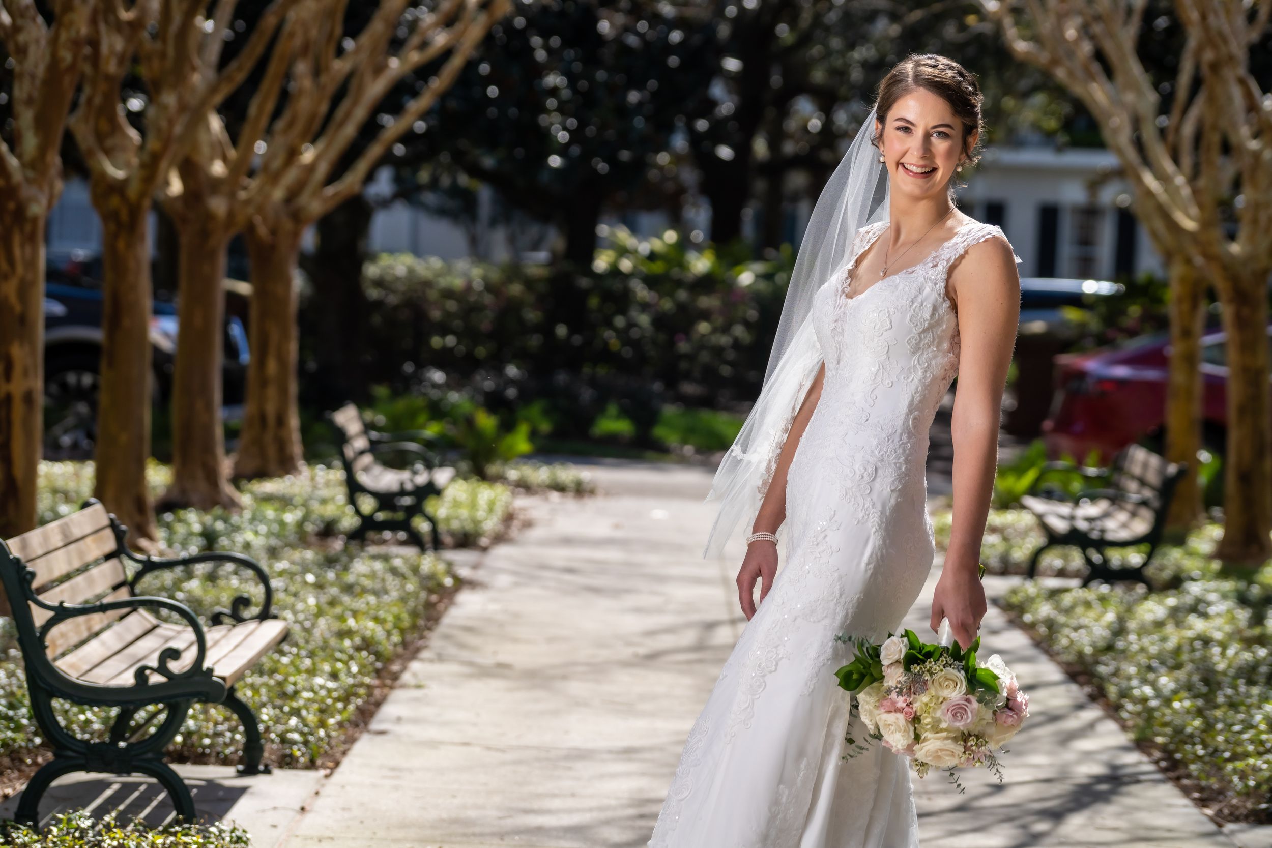 A bridal portrait on a garden pathway framed by trees and holding a bouquet.