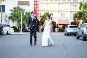 Newlyweds walk hand in hand on city street after wedding ceremony.