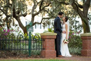 Romantic moment between newlyweds by brick wall and iron fence.
