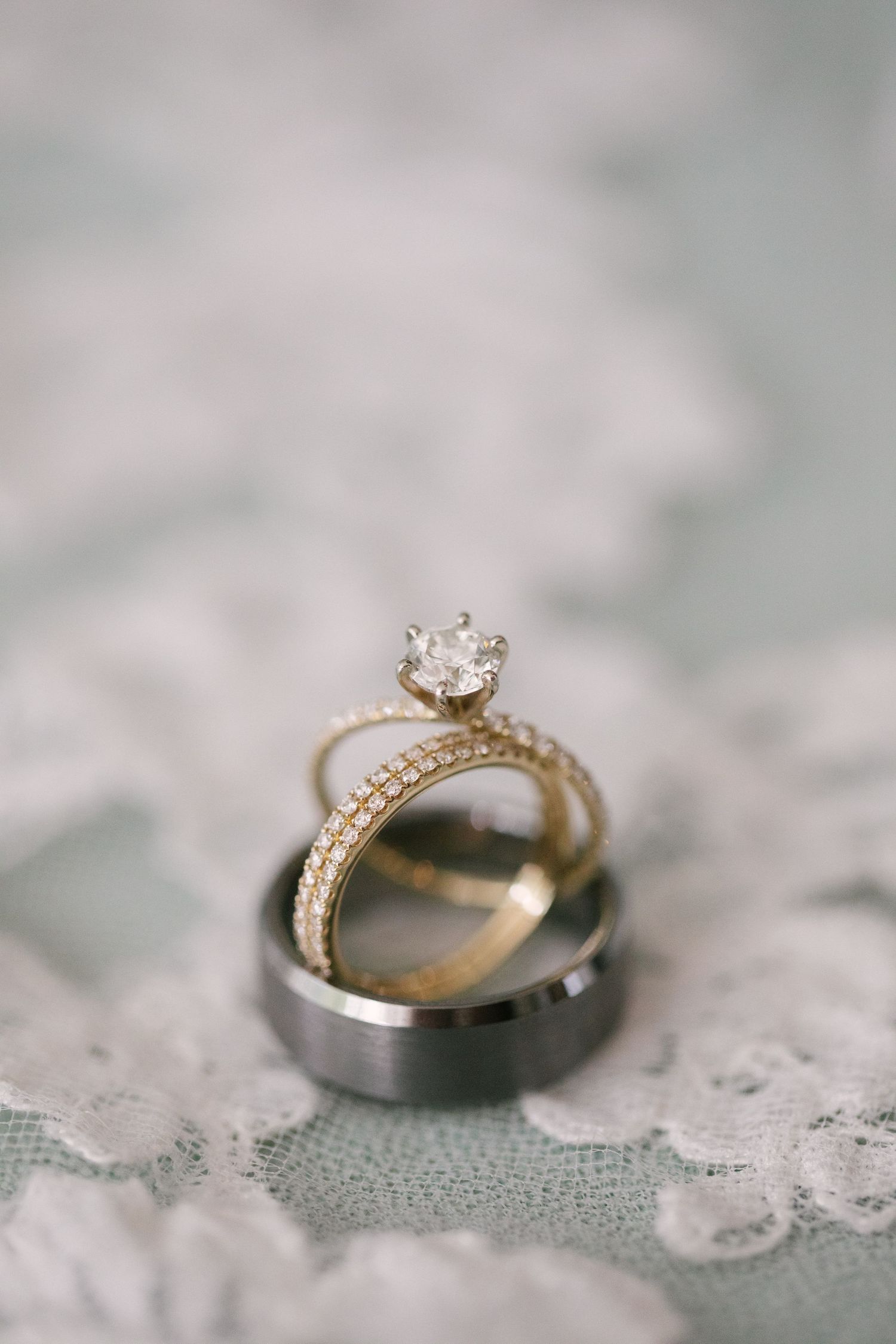 Elegant diamond engagement ring and wedding band photographed on delicate lace fabric.