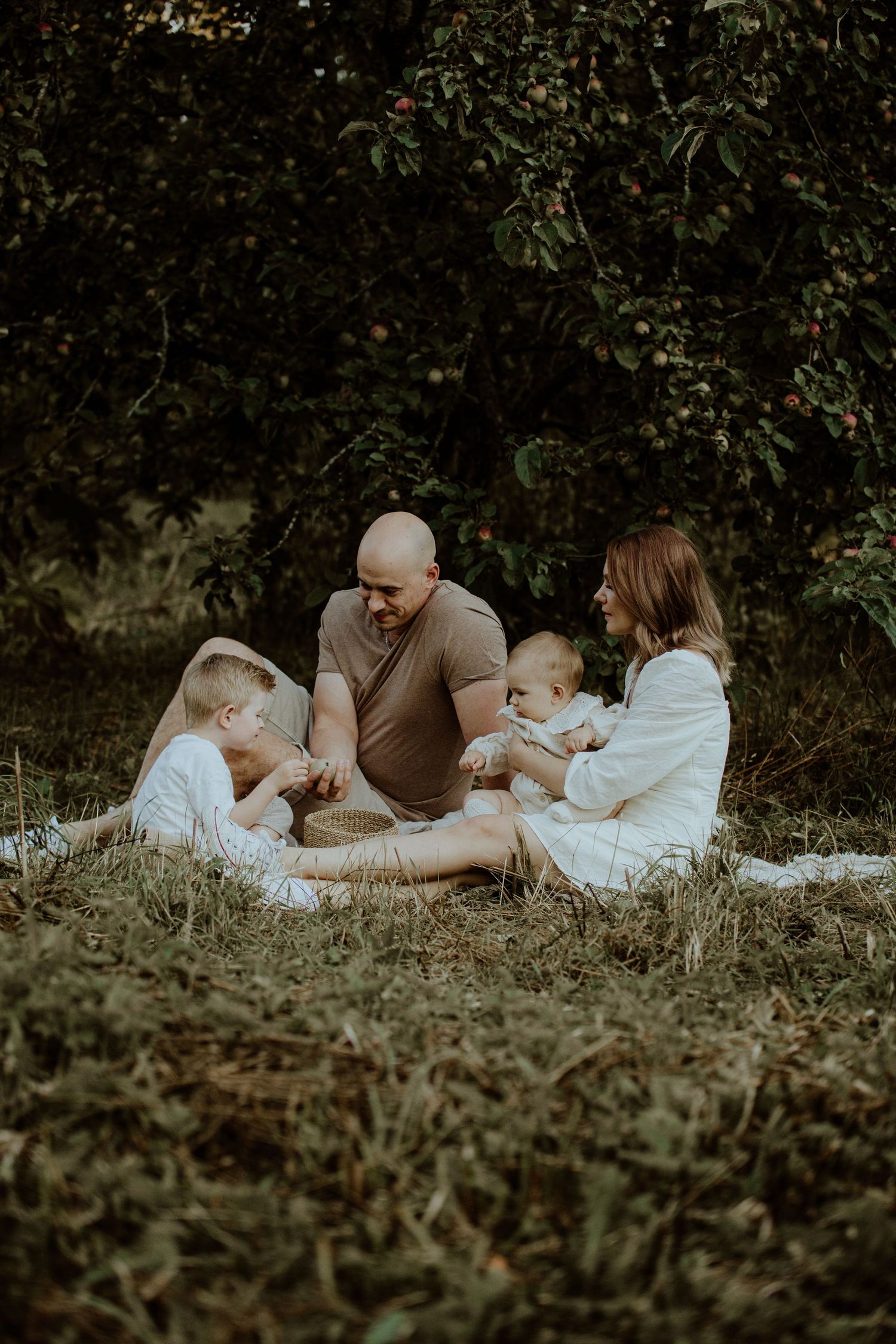 A family relaxes together on a blanket in a peaceful garden setting.