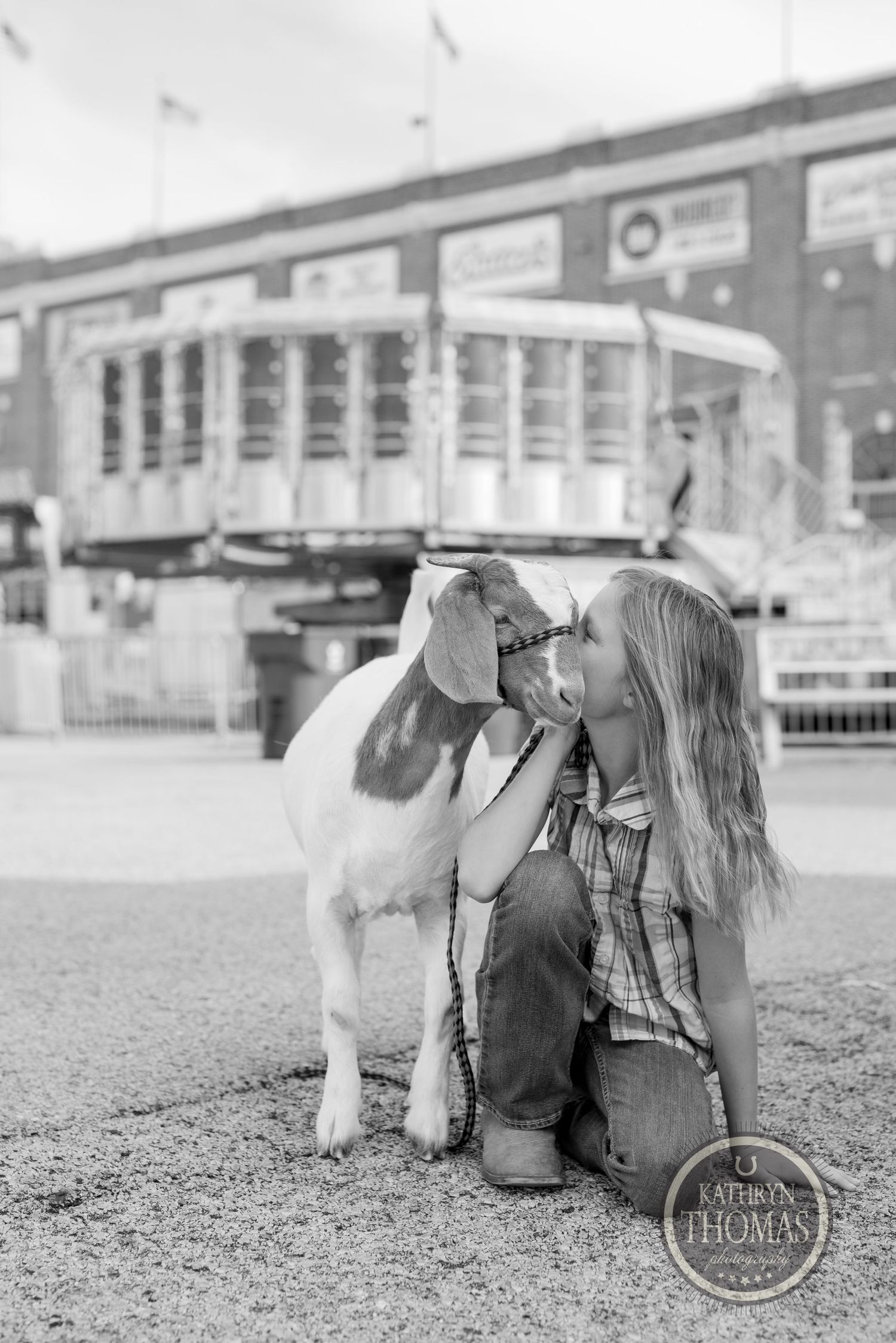 A black and white photo of a young handler bonding with their show goat at a fairground.