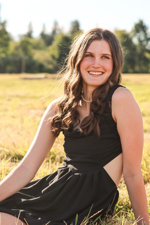 Cora Emilie Media A sunny outdoor portrait in a field wearing a black cutout dress.