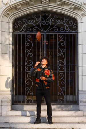 Cora Emilie Media A person in Halloween attire posing with orange balloons against an ornate iron gate.