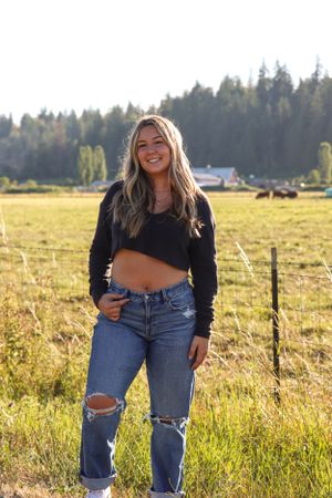 Cora Emilie Media A casual autumn portrait in ripped jeans and crop sweater in a rural field.