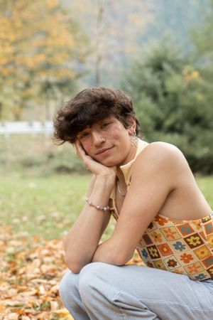 Cora Emilie Media A casual autumn portrait in a patterned top amidst fallen leaves.