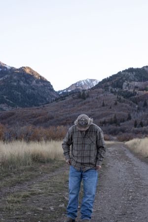 Cora Emilie Media A person in winter attire walks along a mountain trail during golden hour.