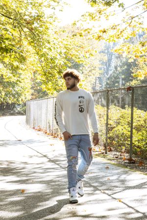 Cora Emilie Media Lifestyle photo of casual street fashion on a sunlit autumn path with falling leaves.