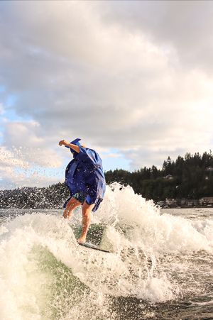 Cora Emilie Media Graduate wakeboarding in full graduation attire creating dramatic splash.