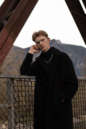 Cora Emilie Media Fashion portrait of person in black coat against mountain backdrop.