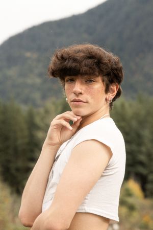 Cora Emilie Media A casual summer portrait against a mountain backdrop wearing a white sleeveless top.