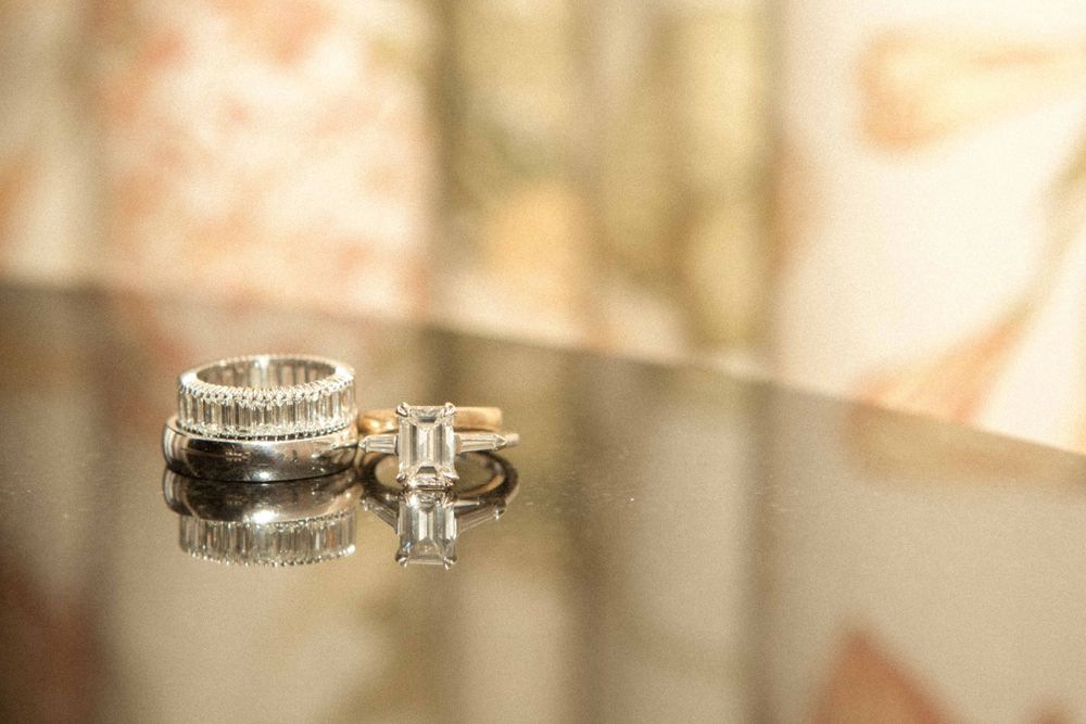 Elegant diamond engagement ring with pave band details photographed in a soft warm light against blurred background.
