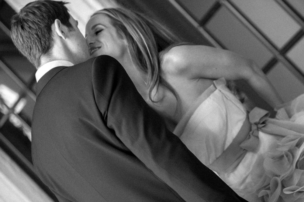 A romantic black and white moment of a couple embracing during their first dance at a wedding reception.