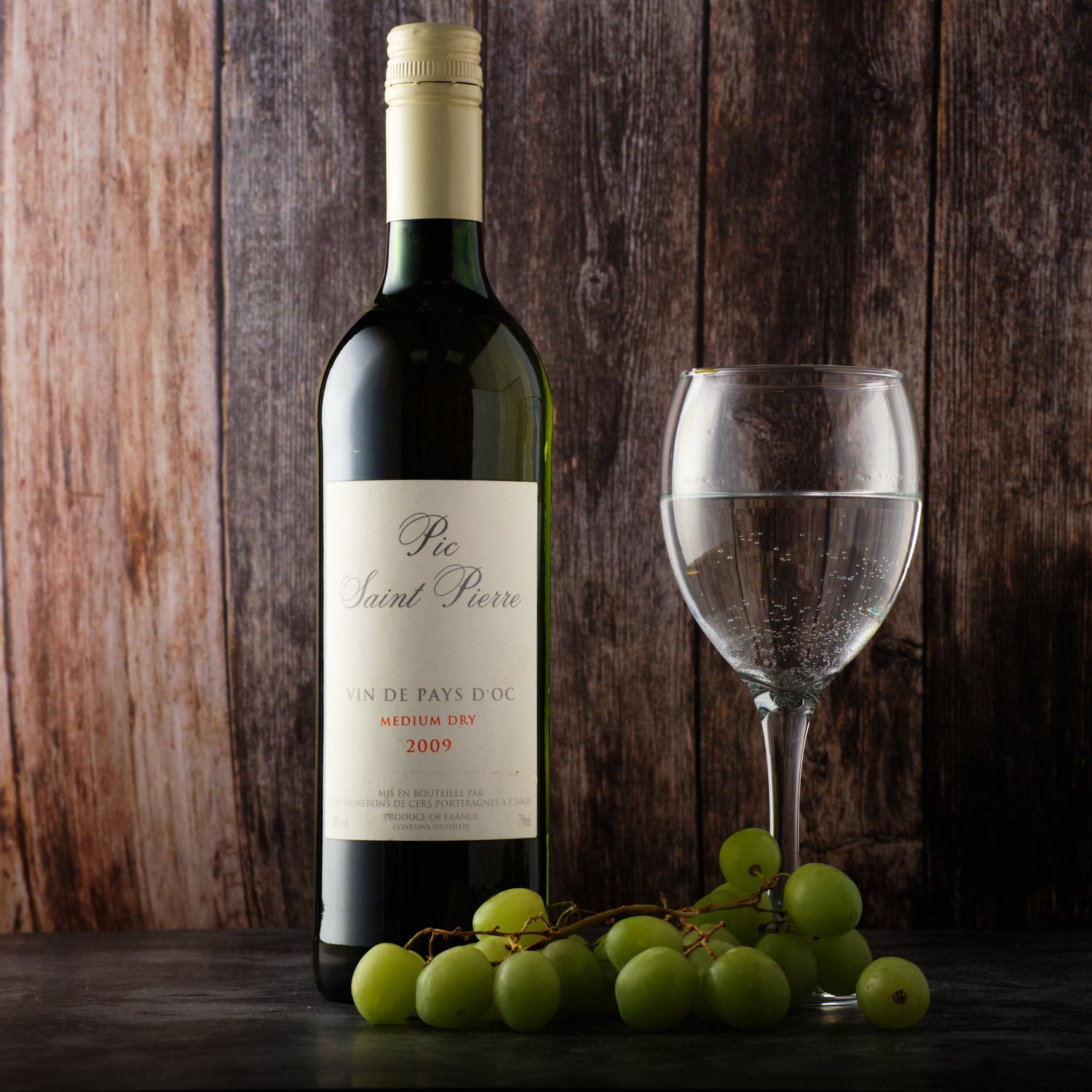 e-Commerce shot of a 2009 Pic Saint Pierre Vin De Pays D'oc in a rustic setting.