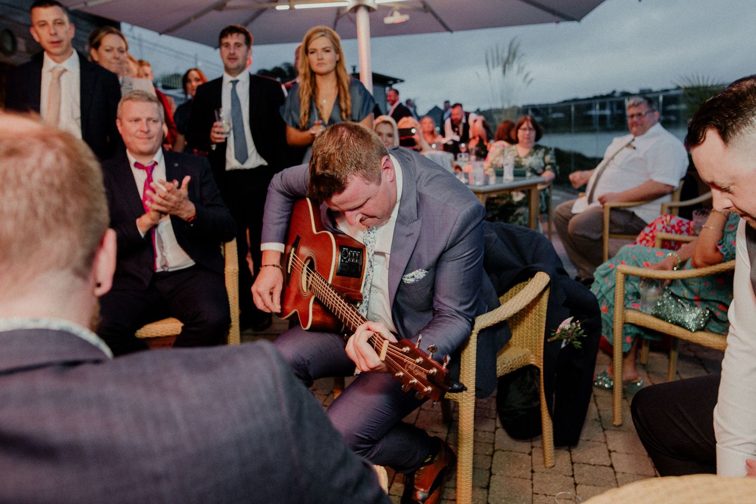 Musicians perform for seated wedding guests on outdoor patio.