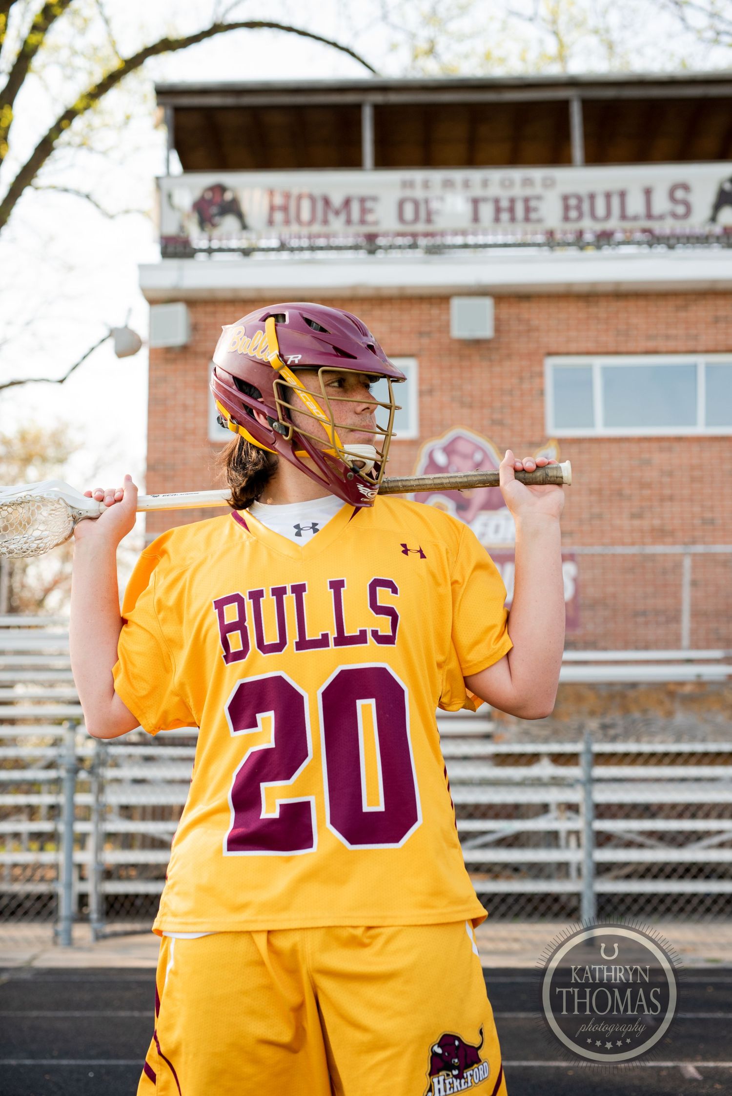 Bulls player number 20 poses with bat in yellow uniform in front of home field sign.