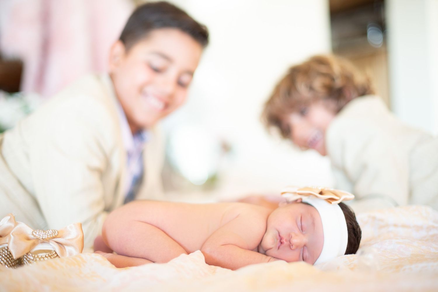 Newborn baby sleeping peacefully on blush pink bedding during professional photoshoot.