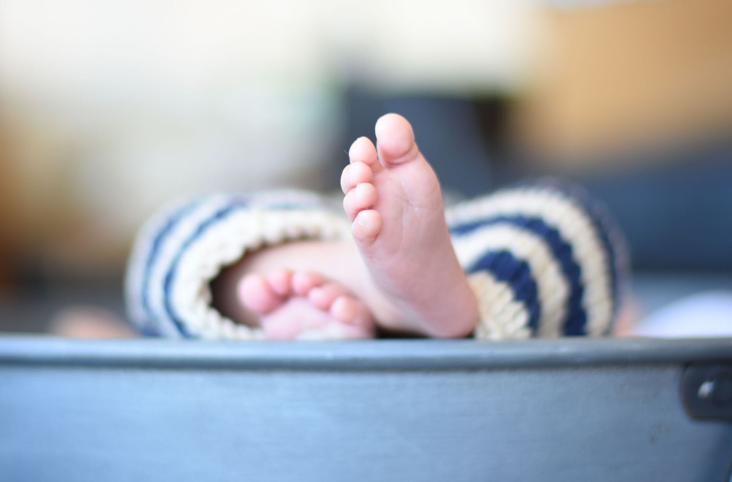 Close-up of baby foot wearing striped knit clothing in gray basket.