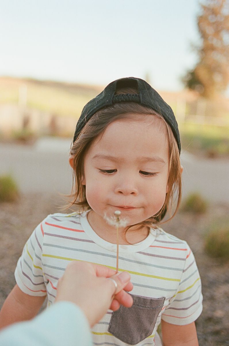 Child drinking from a cup with a straw at sunset.
