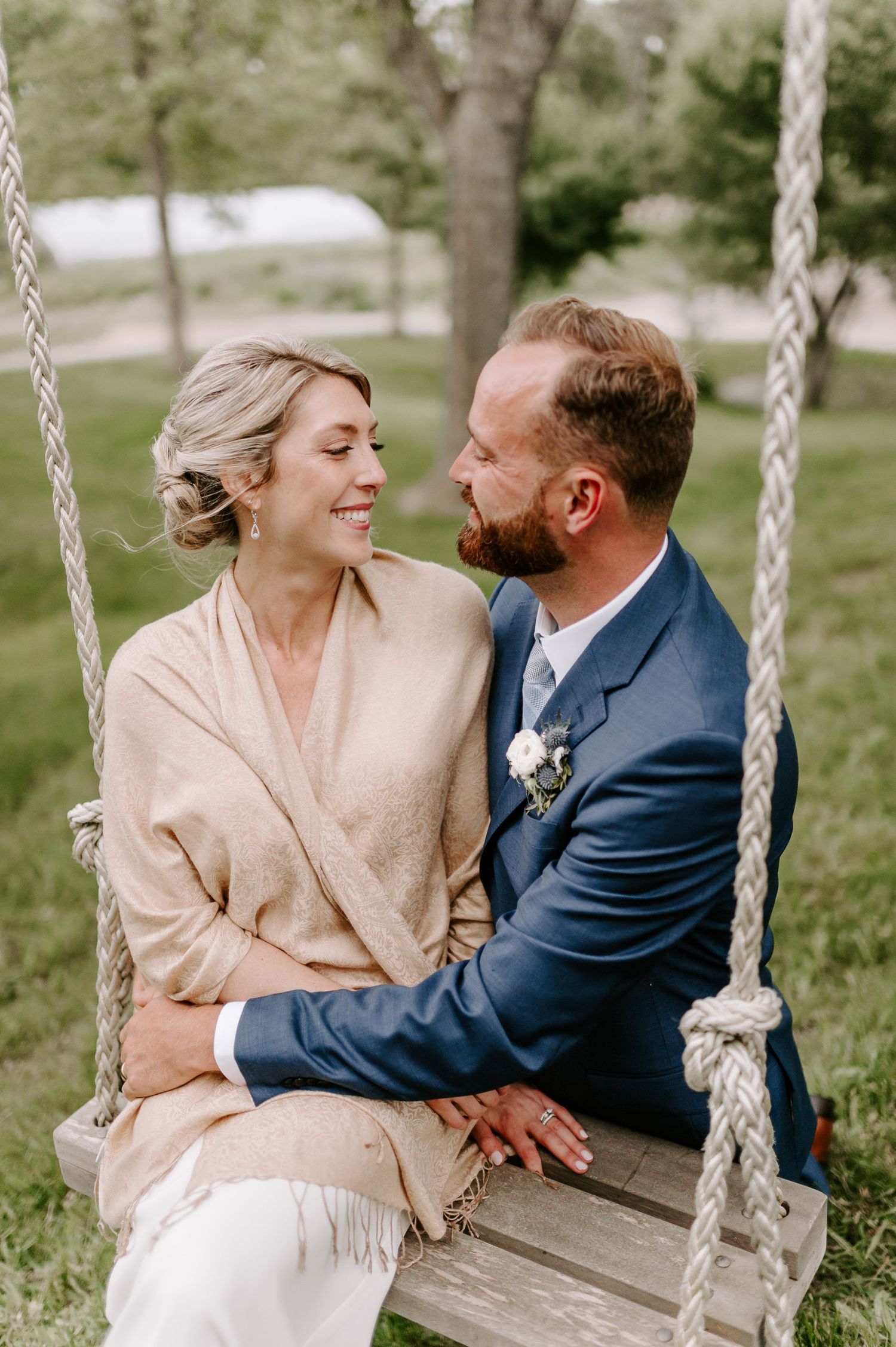 Couple sharing intimate moments on a wooden swing in a garden setting.