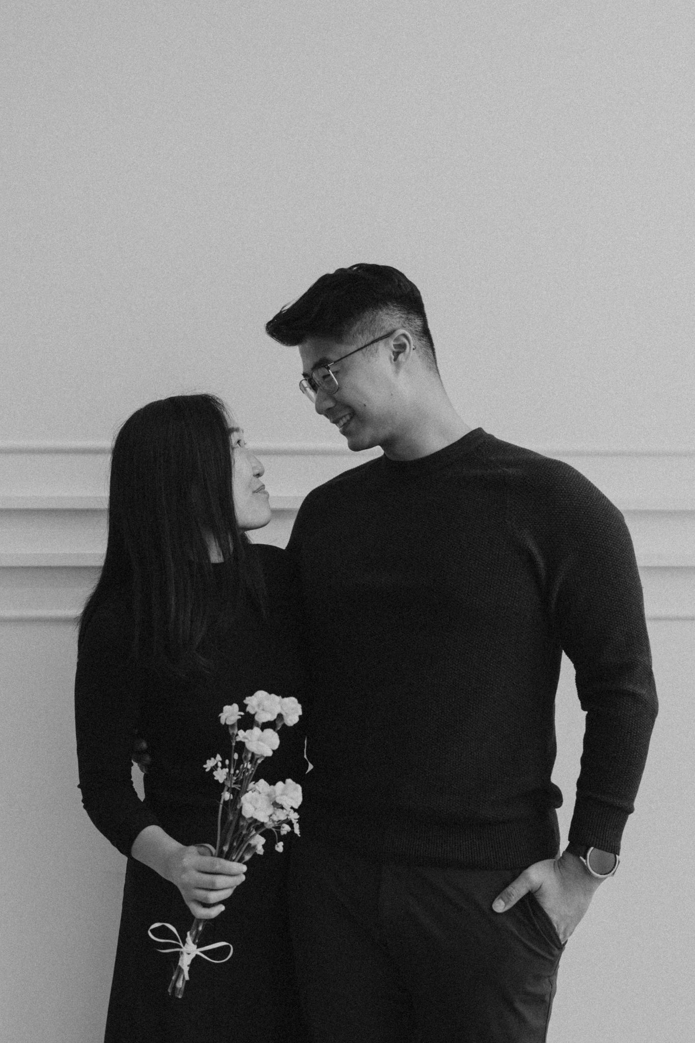 A minimalist black and white photo series showing a couple with white flowers.