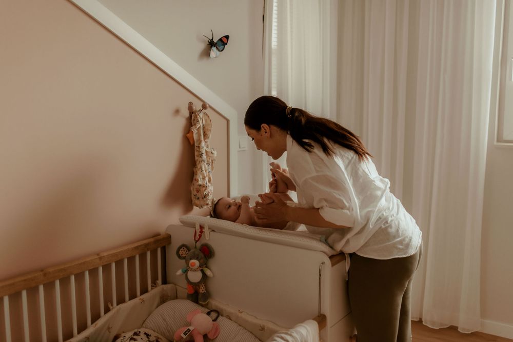 A tender family moment captured in warm sepia tones as parents interact with their infant on a couch.