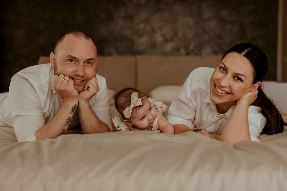 Candid family photography showing joyful moments between parents and baby on a couch.