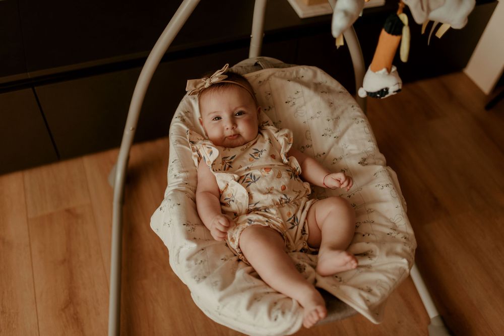 Baby wearing a delicate lace dress lying on wooden flooring during a photo session.