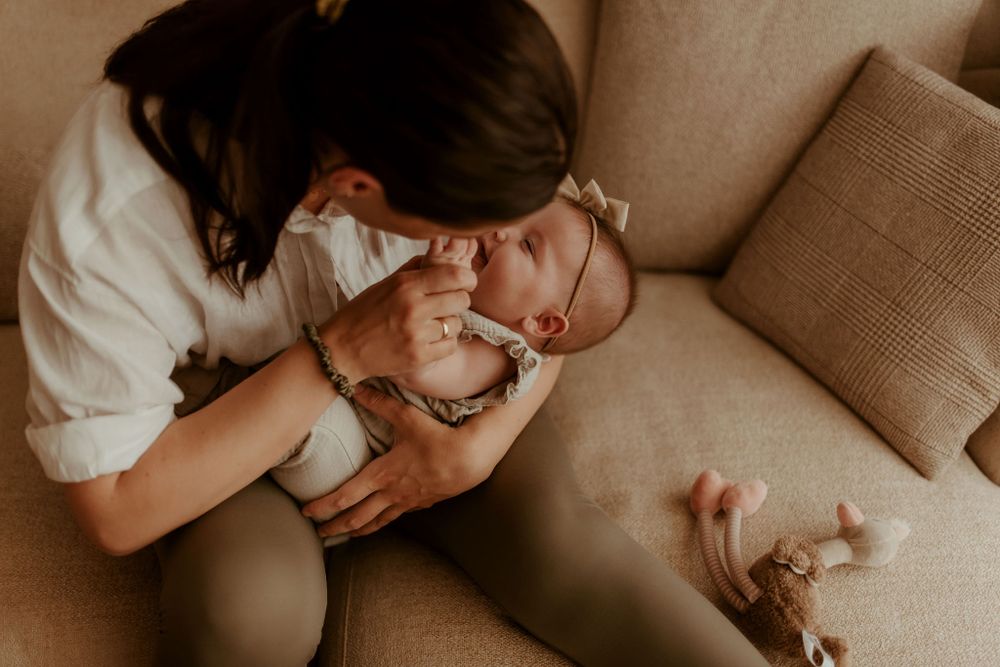 Intimate family moment captured on beige couch in soft lighting.