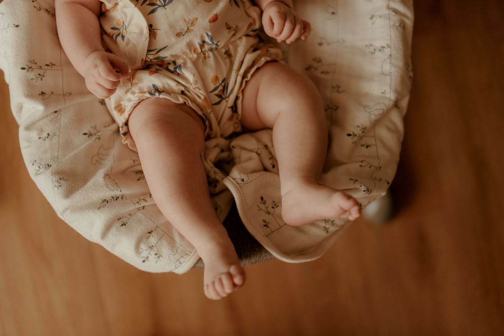 Close-up view of baby's tiny feet and lace dress details during indoor photography session.
