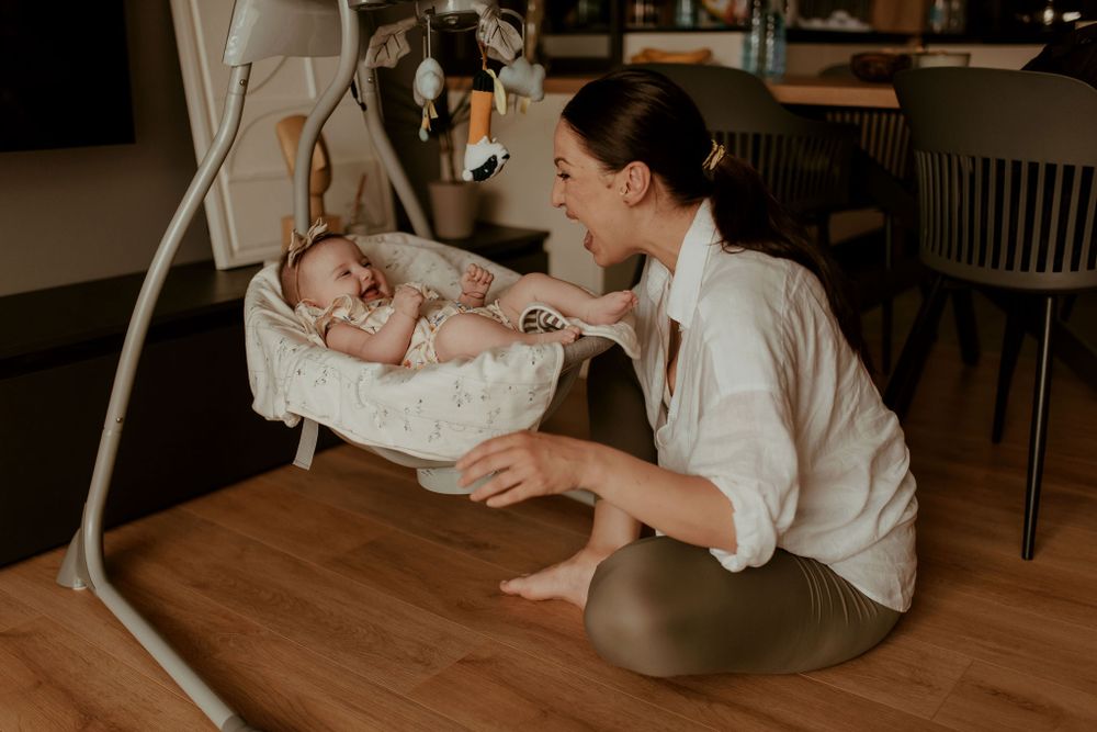Lifestyle photography session on hardwood floors with baby in white lace outfit.