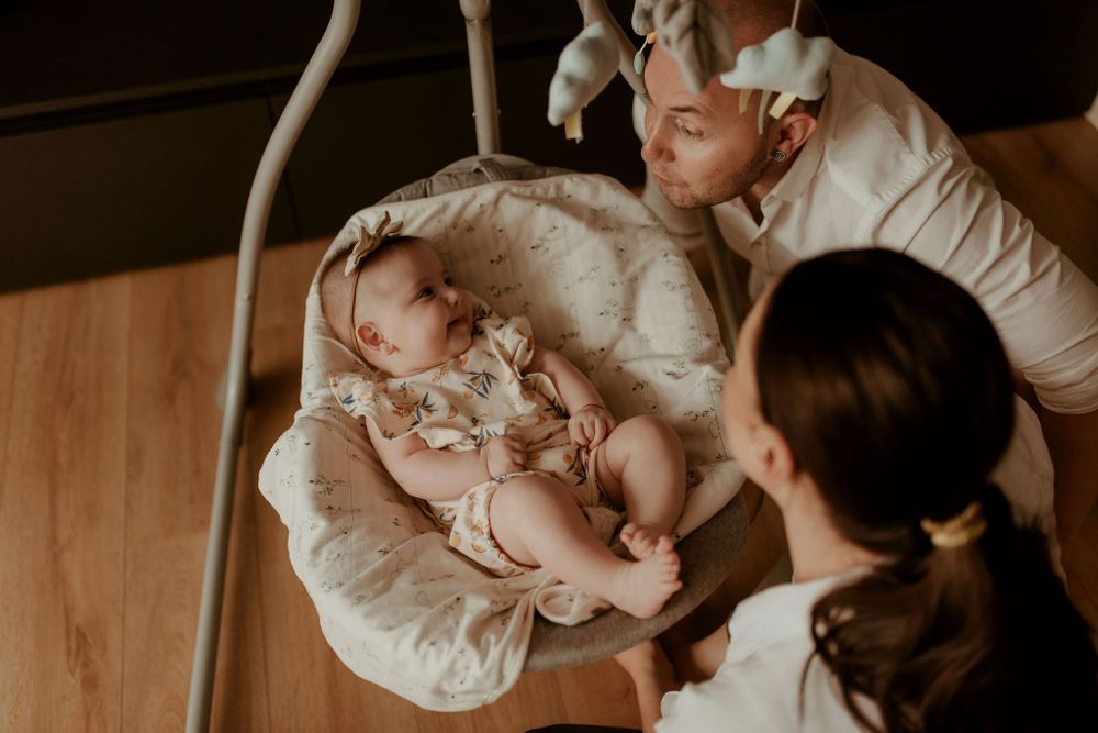 Warm-toned indoor photography showing intimate family interactions on wooden floors.