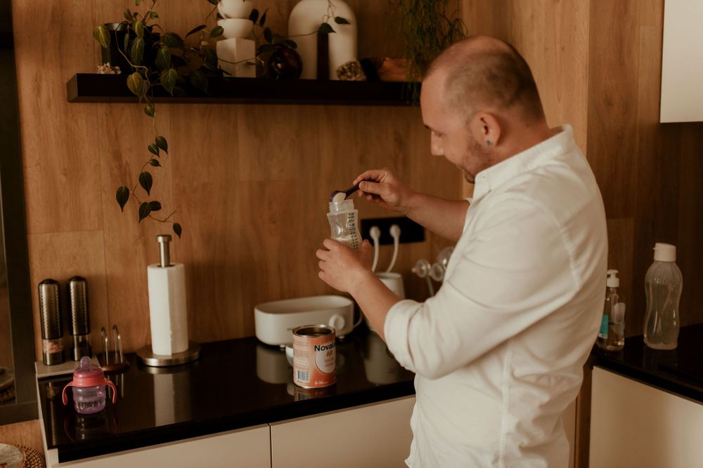 Person in white shirt preparing something in a modern kitchen with wooden accents.