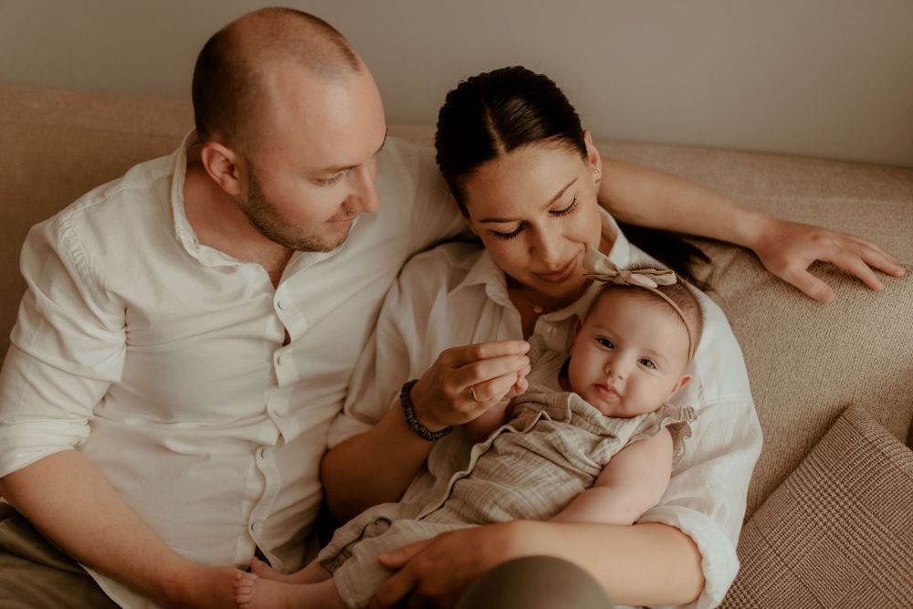 Tender family portrait showing gentle interaction with newborn in muted tones.