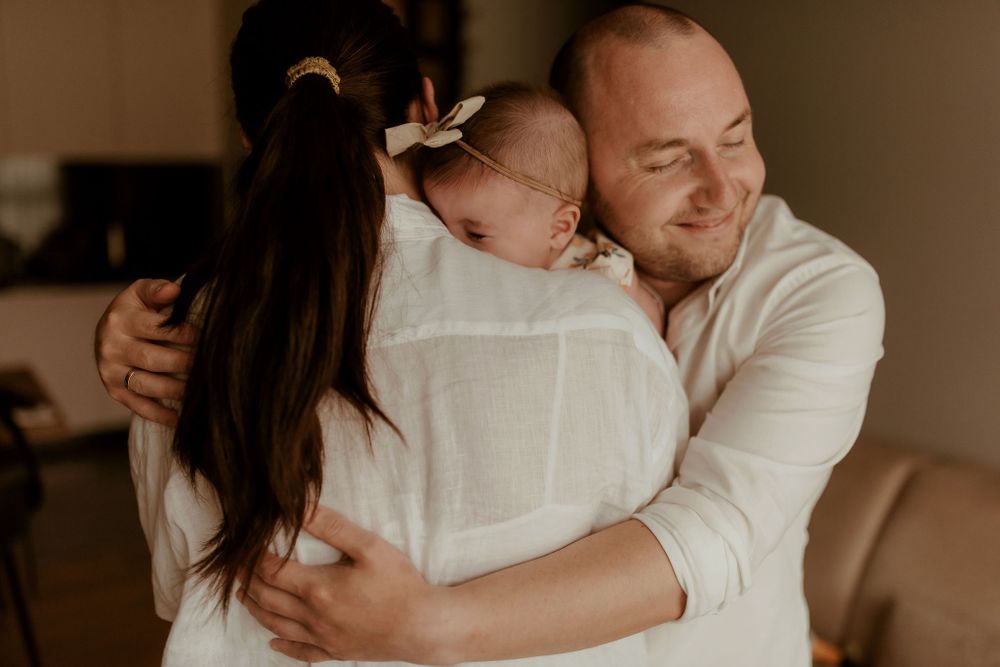 A tender family embrace captured in warm, muted tones on a cozy couch.