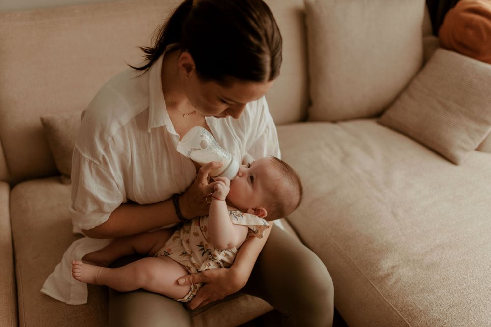 Intimate moment of parent and baby bonding on a comfortable beige sofa.