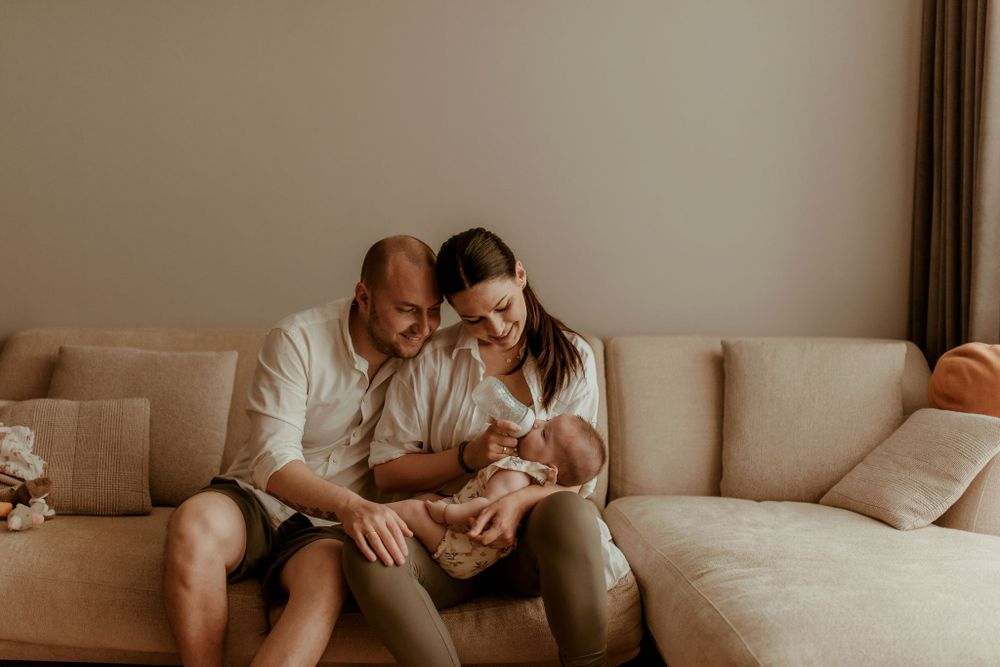 Intimate family portrait on sofa in warm, natural lighting.