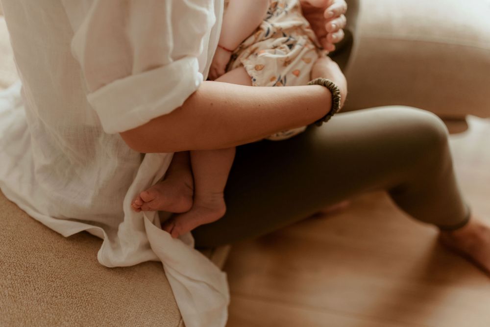 Close-up of tiny baby feet and white fabric on beige couch cushions.